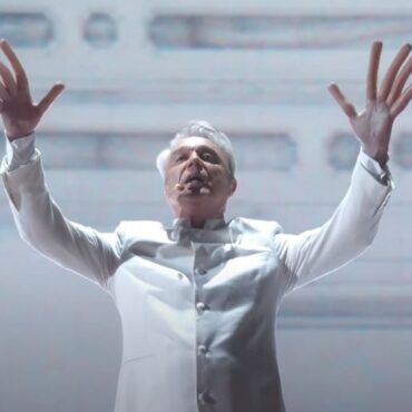 watch:-david-byrne-puts-on-hot-dog-fingers-to-perform-“this-is-a-life”-at-oscars